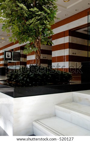 The lobby of a skyscraper, with striped marble walls, and white marble steps