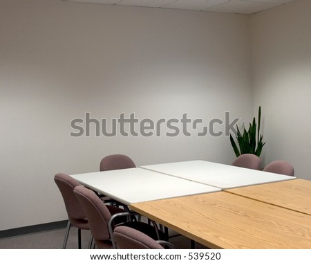 Corner of a conference room, with chairs around an empty table