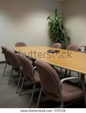 Conference room - vertical shot. Tables surround a long conference table with a plant in the corner.