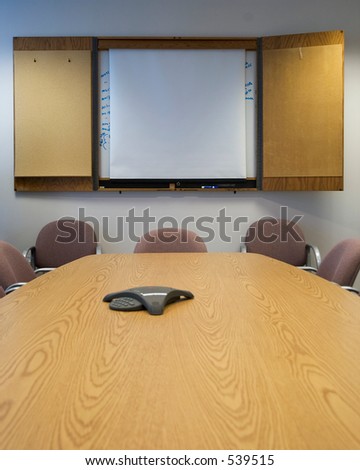 Looking across a long Board room table with a blank whiteboard on the wall.