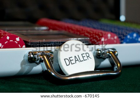 A complete set of poker chips in a case, with cards and dice, with the dealer button in front