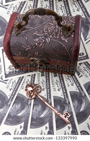 US dollars background wtih a wood treasure chest and old skeleton key/Money savings