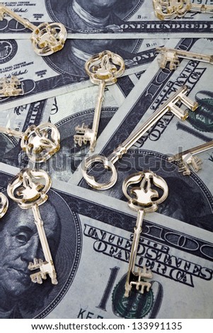 Golden skeleton keys made of plexiglas lie on dollars background/Dollars background with skeleton keys