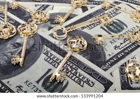 Golden skeleton keys made of plexiglas lie on dollars background. Horizontal orientation./Golden keys on dollars
