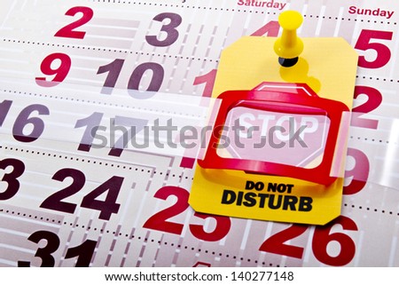 Do not disturb at weekend concept shot. Do not disturb yellow label/tag with a stop road sign on a paper calendar background.