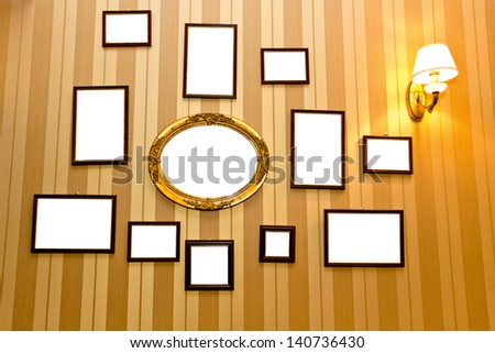 Hanging empty photo-frames on a retro wall with striped wallpapers/Hanging empty photo-frames