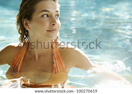 Portrait of a beautiful young woman in a swimming pool under the golden summer light.