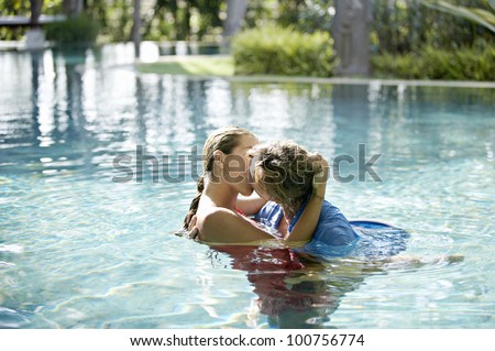 Couple submerged into a swimming pool, kissing and hugging while dressed.