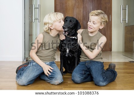 Two brothers at home kissing and hugging their pet dog.
