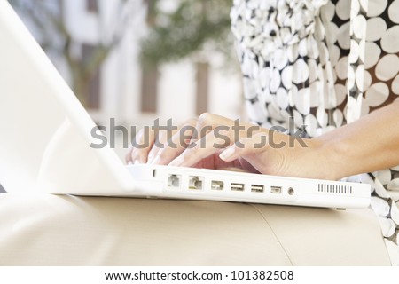 Close up of a businesswoman\'s hands typing on a laptop computer outdoors.