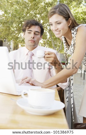 Two business people having a meeting in an outdoors cafeteria in the city, smiling.