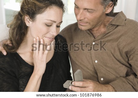 Close up of a mature man proposing marriage to a woman and offering her an engagement ring.