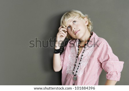 Quirky young boy looking thoughtful on a brown background.