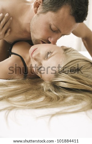 Close up portrait of an attractive young couple kissing in bed.