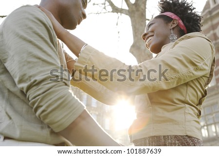 Young couple holding each other in the city with the sunset sun filtering through their bodies.