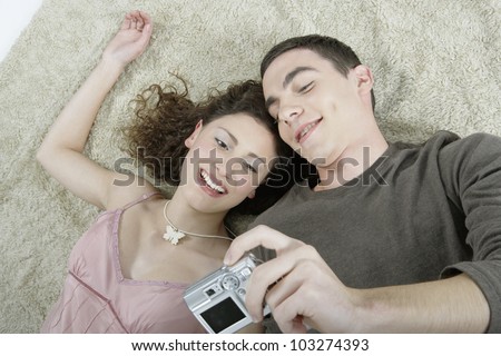 Over head view of a young couple taking pictures of themselves with a digital photo camera.
