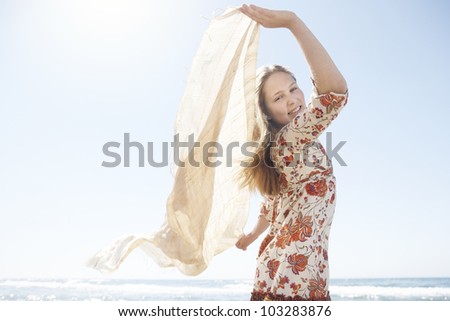 Girl holding a floating sarong in the air, smiling at the camera.