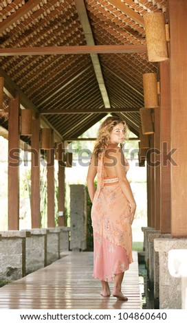 Attractive woman walking down a wooden walkway in a tropical holiday villa.