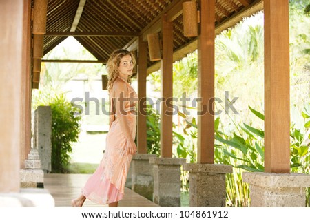 Attractive woman walking down a wooden walkway in a tropical holiday villa.
