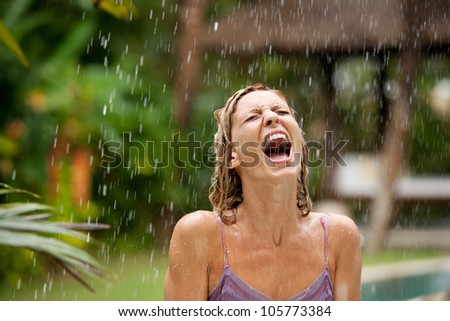 Attractive woman under tropical rain in an exotic garden, screaming.