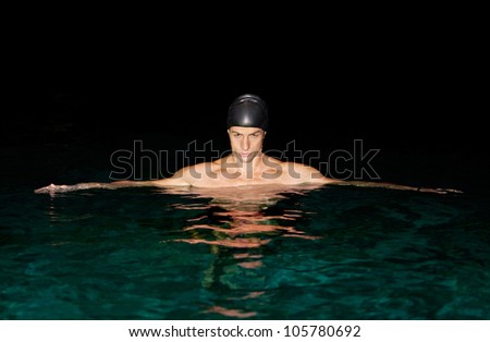 Man preparing for swimming training in a swimming pool at night.
