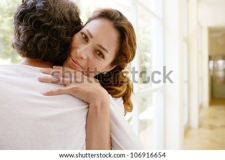 Mature couple hugging in a garden corridor at home.