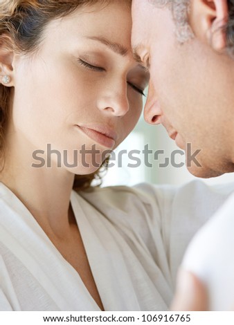 Close up of a  mature couple hugging at home, with their foreheads together.