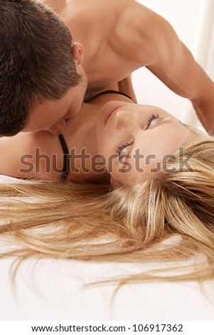 Young couple kissing and hugging in bed.
