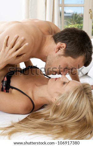 Young couple kissing and hugging in bed.