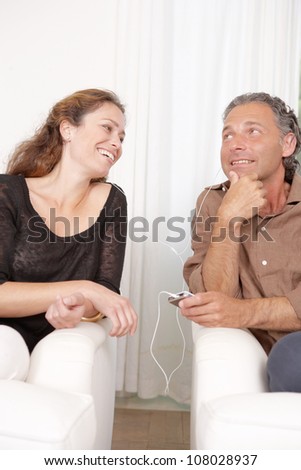 Mature couple sharing headphones while listening to music at home.