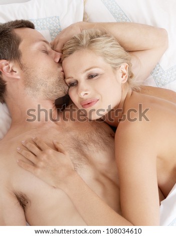 Young attractive man kissing woman\'s forehead in bed.