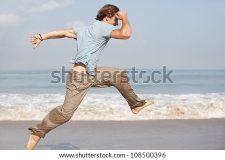 Attractive young man jumping by the sea shore while on holiday.
