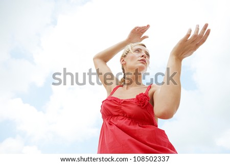 Under view of an attractive woman practicing martial arts against a blue sky.