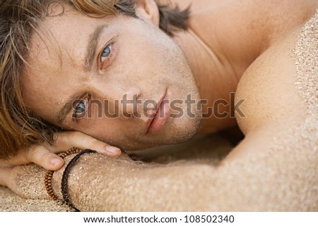 Close up portrait of an attractive young man sunbathing on the beach.