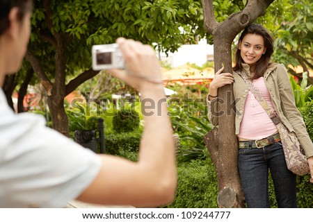 Young couple taking pictures of each other while in a park on holidays.