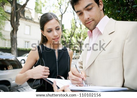 Two business people meeting outdoors in a tree aligned street.