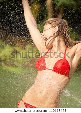 Attractive young woman enjoying the splashing of water on her body while on vacations in a tropical destination.