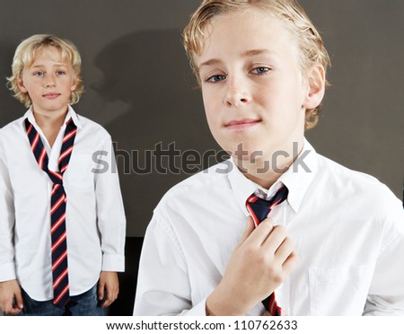 Two brothers getting ready for school at home, wearing uniform shirts and tightening a tie.