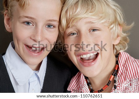 Close up portrait of two young brothers laughing with their heads together.