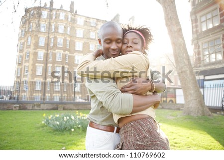 Young black couple hugging in a park at sunset, while visiting London city.