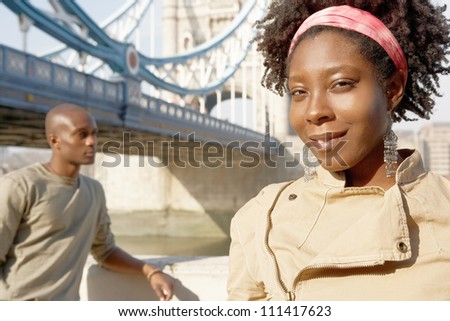 Portrait of an african american man and woman standing by Tower Bridge while sightseeing in London.