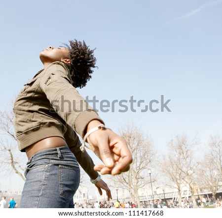 Attractive black woman expressing freedom against an intense blue sky, bending backwards with her arms stretched.