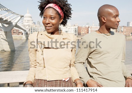 Portrait of a quirky black couple on vacations, visiting London city with the Millennium Bridge and St Paul\'s Cathedral behind them.