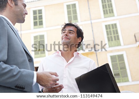 Portrait of two businessmen having a conversation while standing next to a classic building in the city.