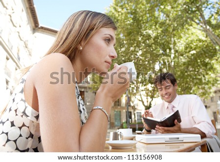 Business people having a coffee while sitting at a coffee shop table in a town square.