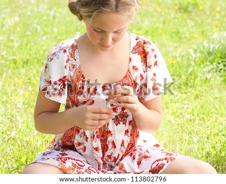 Young teenager pulling petals off a daisy flower, playing at love me love me not.