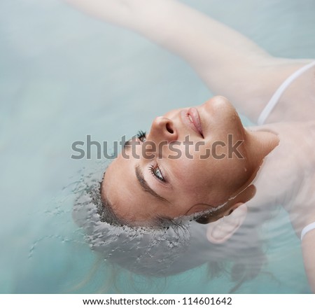 Close up over head view of a young woman floating in water while in a swimming pool on vacation.
