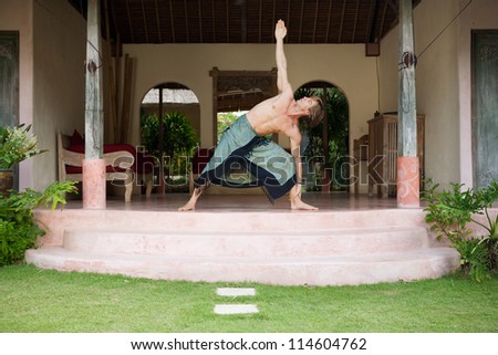 Attractive man doing yoga and stretching while on a holiday villa's garden, outdoors.