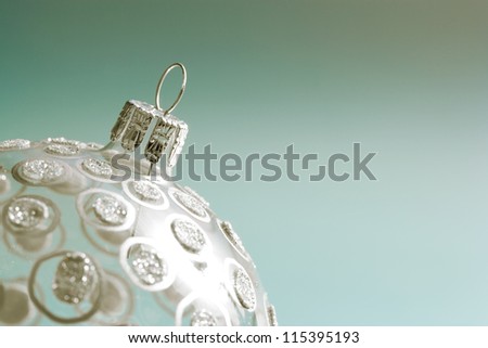 Close up view of a luxury glass and glitter Christmas tree ball ornament with silver spots isolated against a green background.