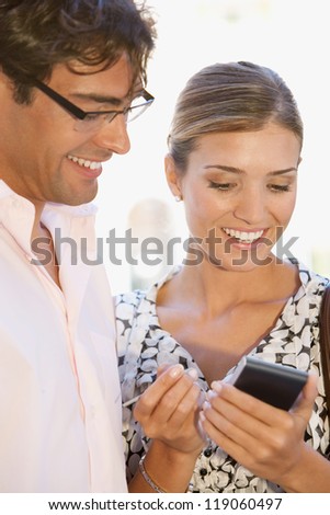 Team of two busy business people gathering around in a casual meeting outdoors, using a digital device to work.